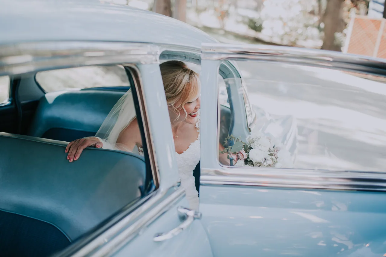A couple seated in a classic car on their wedding day