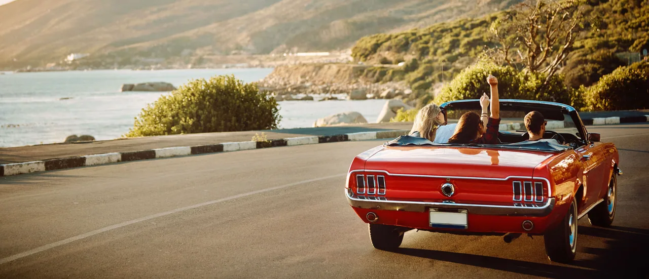 A classic car on an open, scenic road